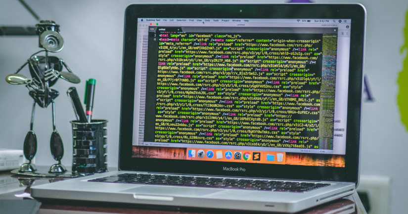 A laptop on a desk displaying HTML source code
